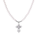 White pearl beaded necklace with ornate crystal-embellished cross pendant on white background, white gold plated finish