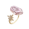 Adjustable gold ring with pink baroque freshwater pearl and crystal-studded star charm on white background