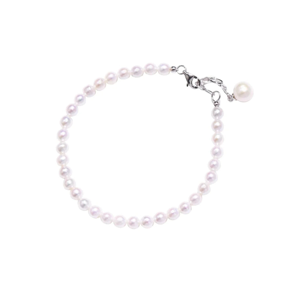 Delicate freshwater pearl bracelet with rhodium-plated silver clasp and single pearl drop charm on cream background