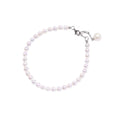 Delicate freshwater pearl bracelet with rhodium-plated silver clasp and single pearl drop charm on cream background