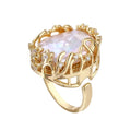 Gold filigree crown ring cradling an iridescent baroque freshwater pearl with crystal accents on white background
