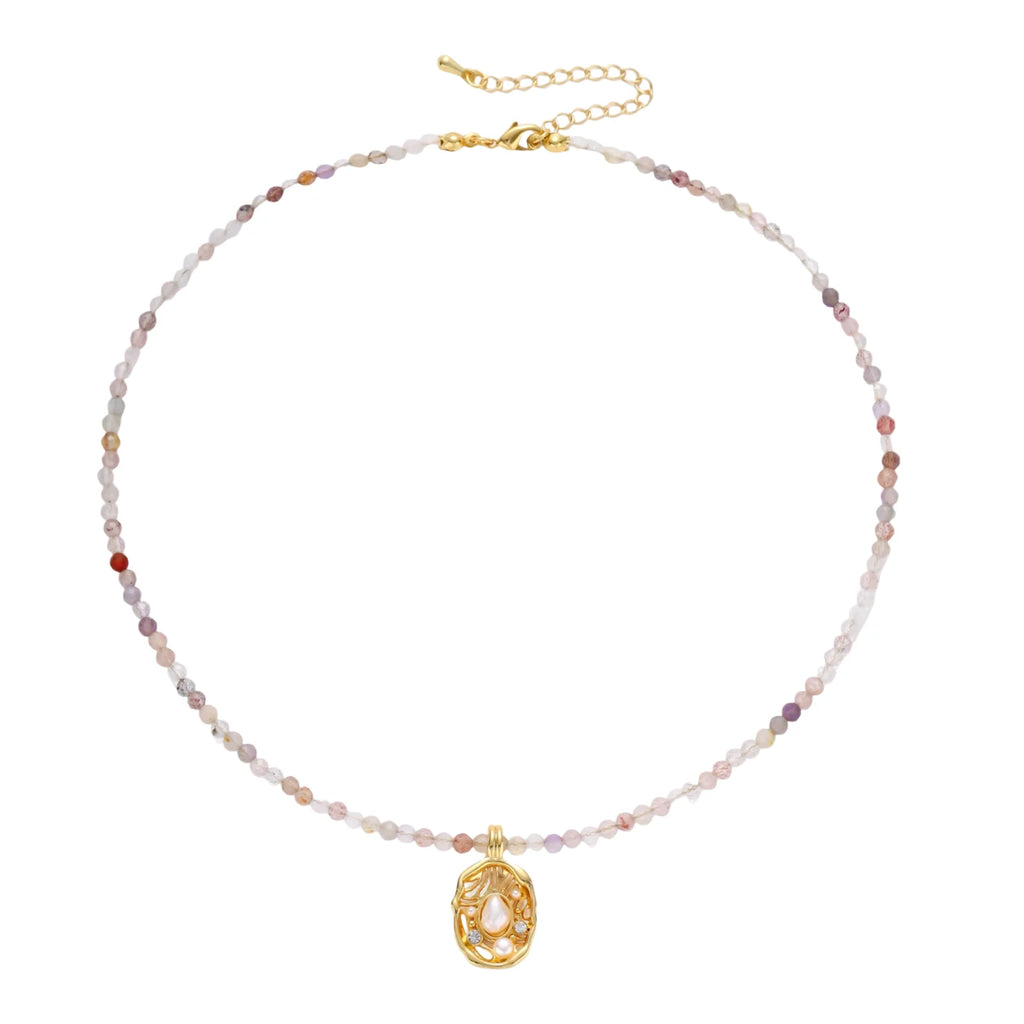 Delicate gold-plated necklace with mixed gemstone beads and ornate oval pendant on white background
