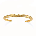 Polished 18K gold plated cuff bracelet with cubic zirconia set in star motifs on a cream background.